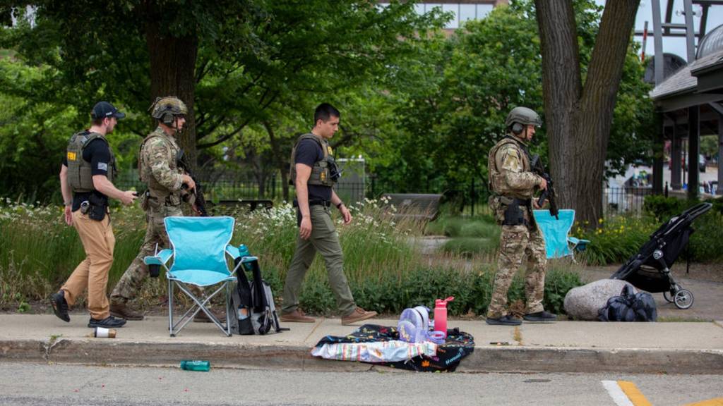 Police walk past strollers and picnic chairs in Highland Park