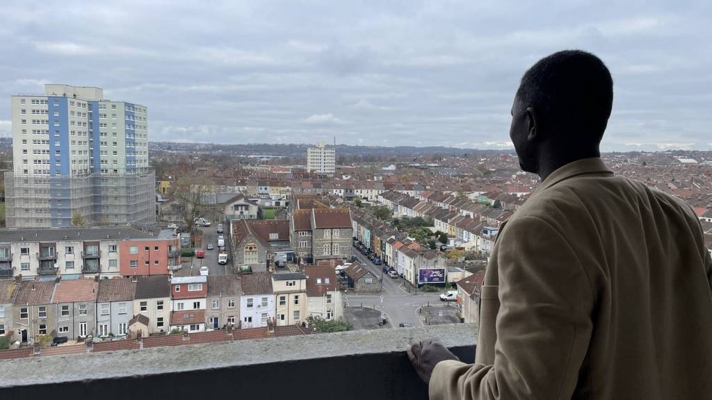 A man looking at the Barton House tower block from another building