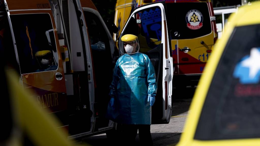 A health worker waits in a protective suit among the ambulances at the Gregorio Marañón hospital on May 13, 2020 in Madrid, Spain
