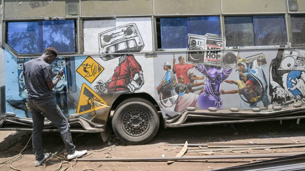 An artist uses an air brush to put final touches on a matatu at a garage in Nairobi, Kenya - October 2023