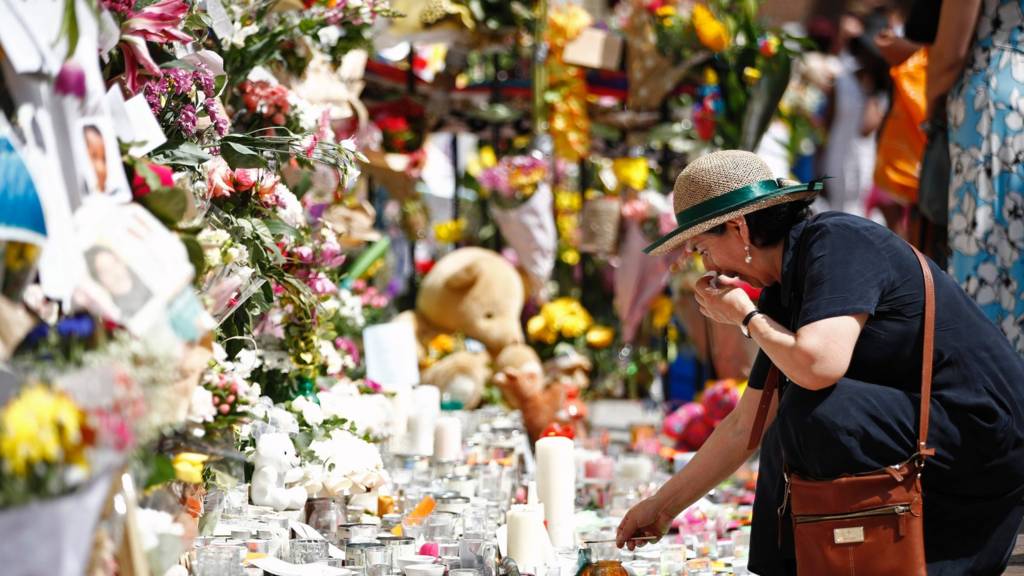 A woman lays flowers in tribute to the victims of the June 14 Grenfell Tower block fire in Kensington, west London, 17 June