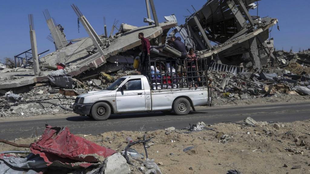 Internally displaced Palestinians drive past destroyed buildings as they leave with their belongings following an evacuation order issued by the Israeli army, in Rafah