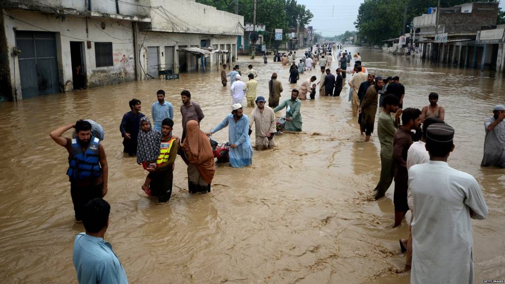 Displaced people wade through a flooded area in Peshawar, Khyber Pakhtunkhwa, Pakistan on 27 August 2022