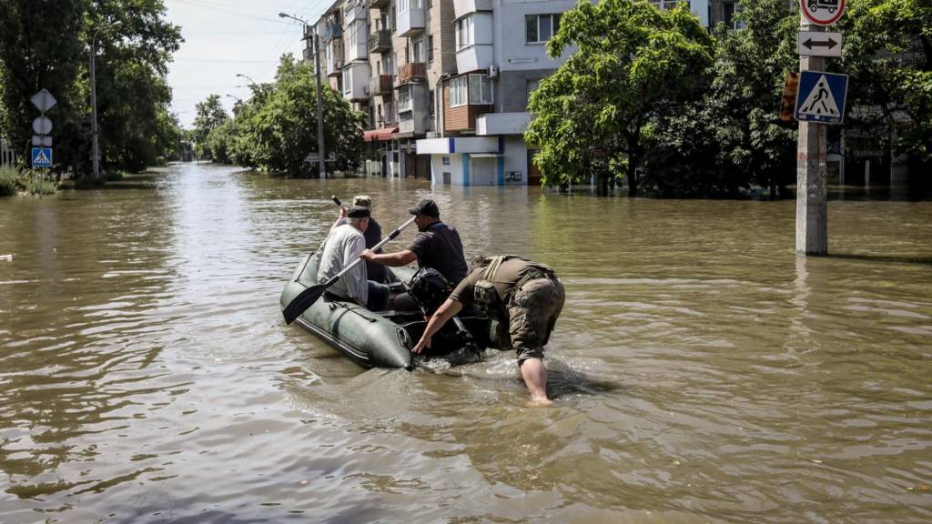 People move on a rubber boat along the flooded streets of Kherson