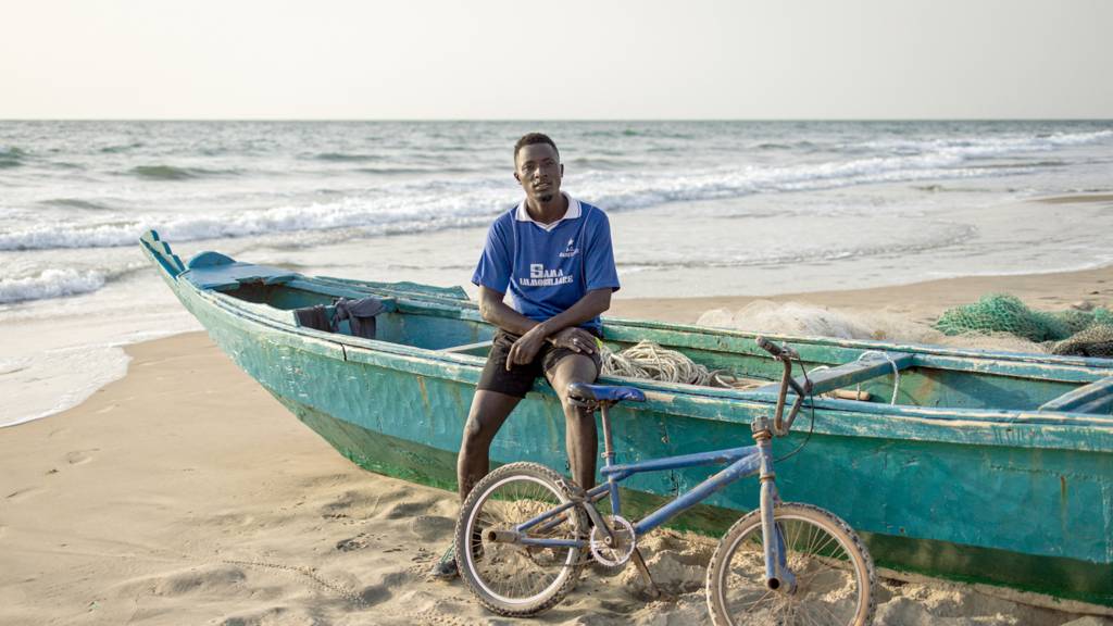 A man poses with his bike for a portrait along a beach in Banjul , The Gambia - 4 May 2024