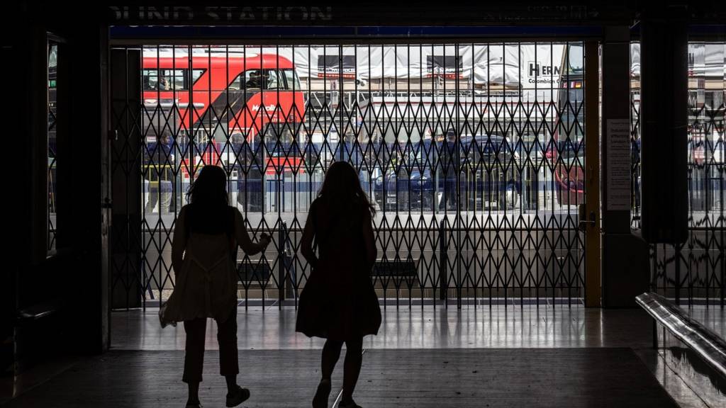 Women walk past gates blocking the entrance to Victoria underground station on June 21, 2022 in London, United Kingdom.