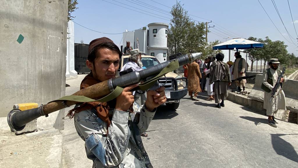 A Taliban fighter stands guard with others at an entrance gate outside the Interior Ministry in Kabul on 17 August 2021