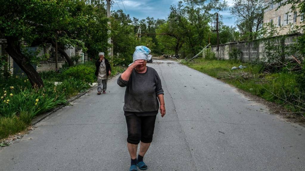 Woman crying in Severodonetsk as her daughter leaves on a van 25 May 2022