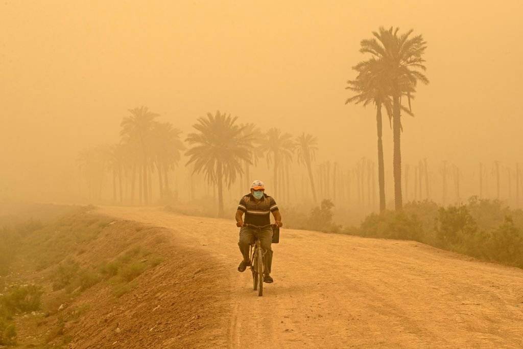 رجل يركب دراجته خلال العاصفة الرملية