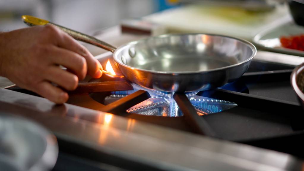 A person lights a gas stove