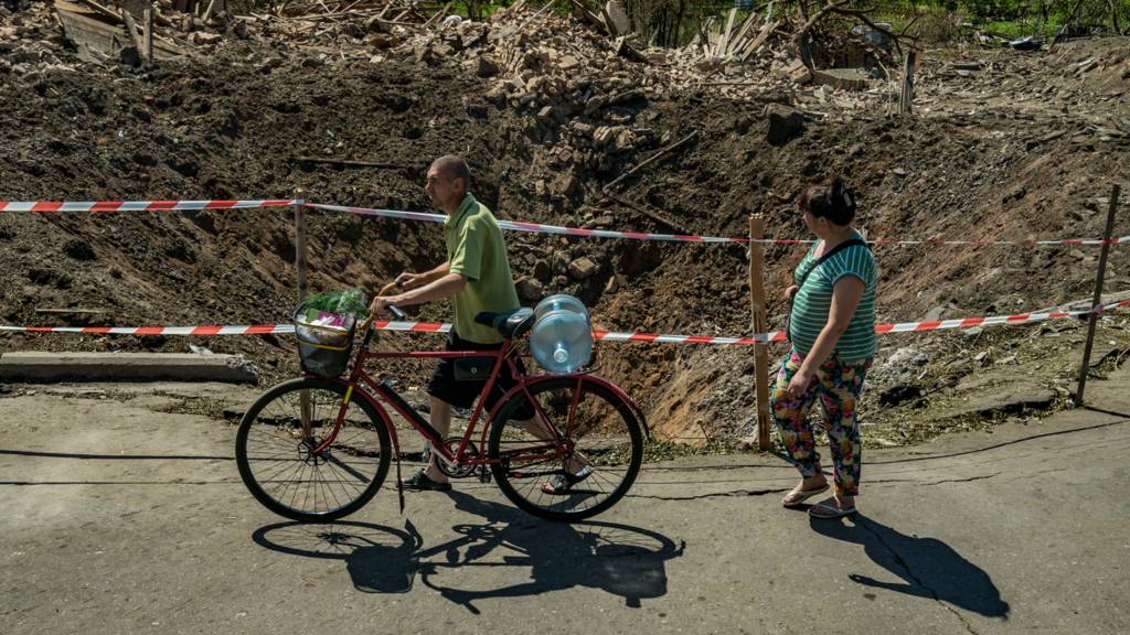 Civilians pass near a huge crater in Druzhkivka