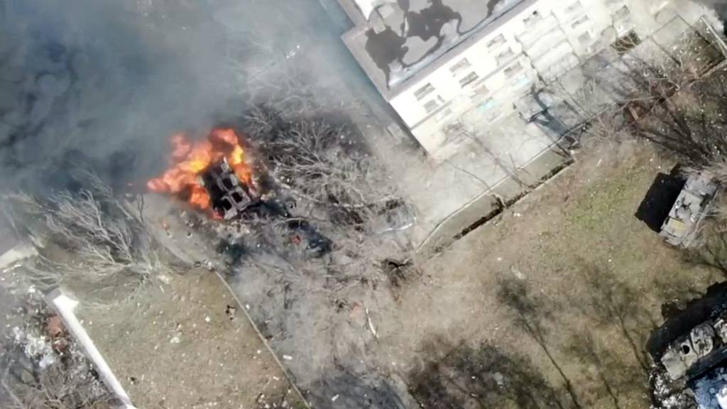 An aeriel view shows a military vehicle on fire next to a building, as Russia's invasion of Ukraine continues, in Maripuol, Ukraine as uploaded on 13 March 2022