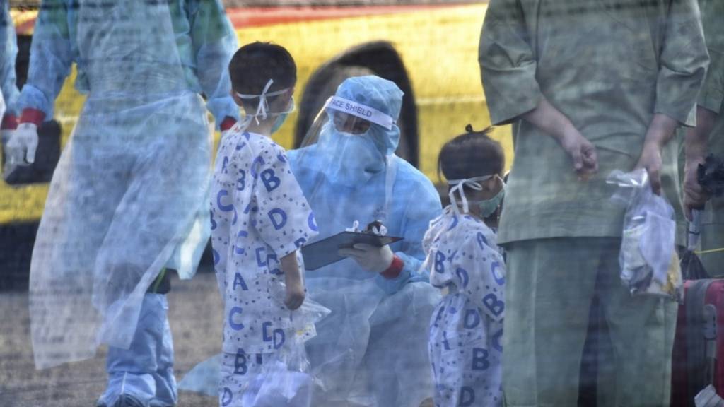 Health workers inspecting young passengers arriving from Wuhan, China, at Kuala Lumpur International Airport