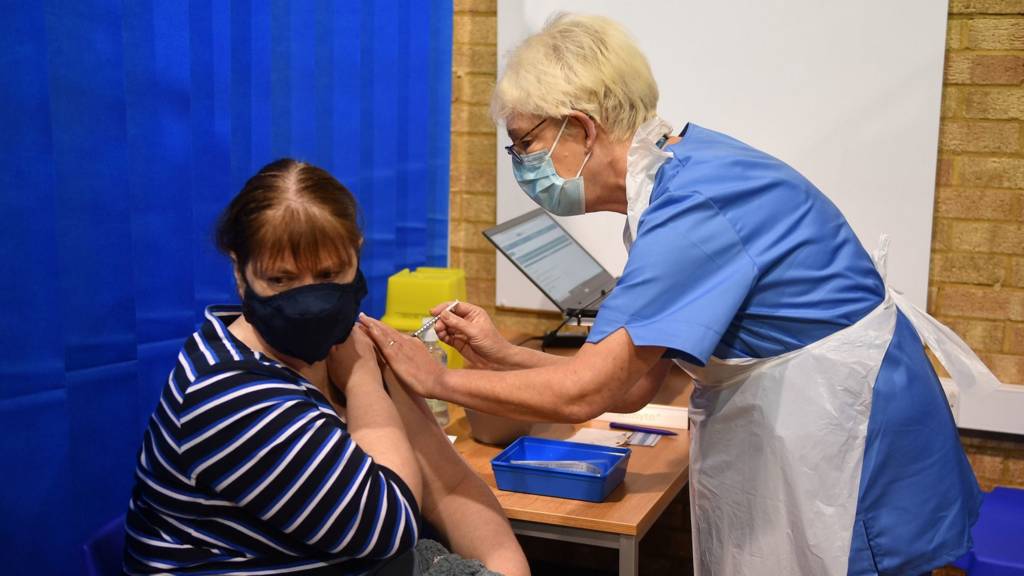 A nurse administers a vaccine to a woman in England