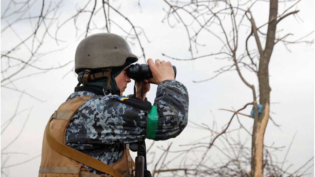 A Ukrainian serviceman looks on with a binocular, as Russia's attack on Ukraine continues, at a position in Donetsk Region