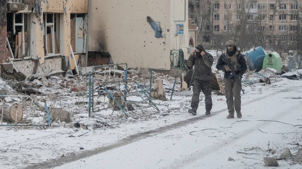 Ukrainian servicemen walk an empty street near buildings damaged by a Russian military strike, in the front line city of Vuhledar