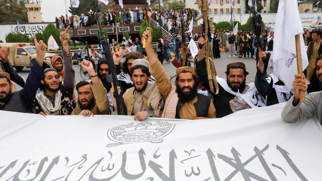 Taliban fighters hold an Islamic Emirate of Afghanistan flag on the first anniversary of the fall of Kabul on a street in Kabul, Afghanistan, on 15 August 2022