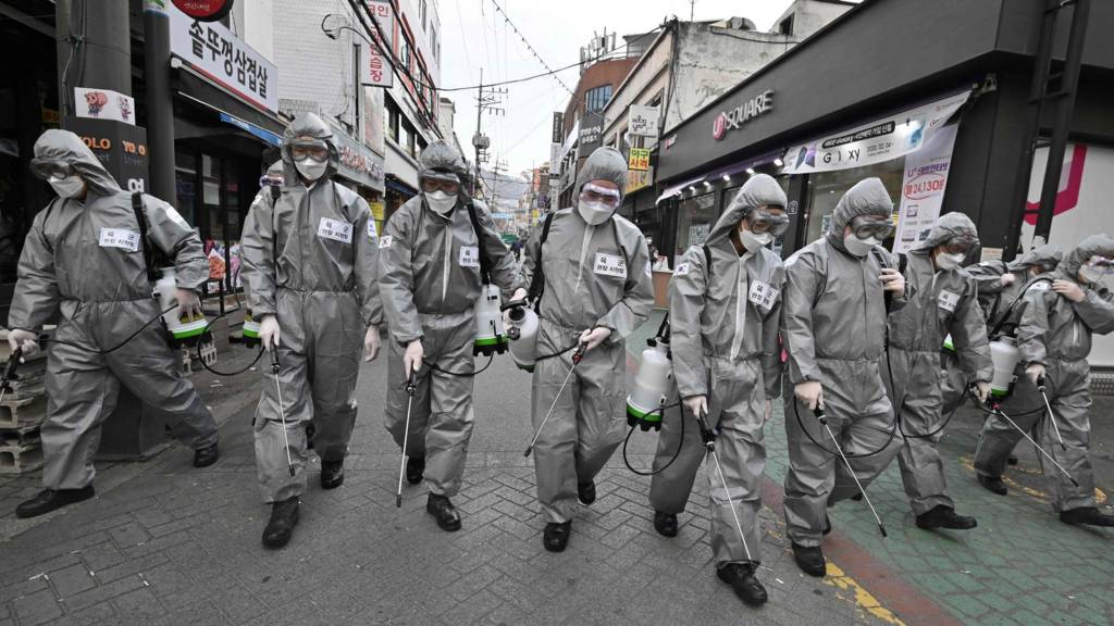 South Korean soldiers wearing protective gear spray disinfectant at a shopping district in Seoul