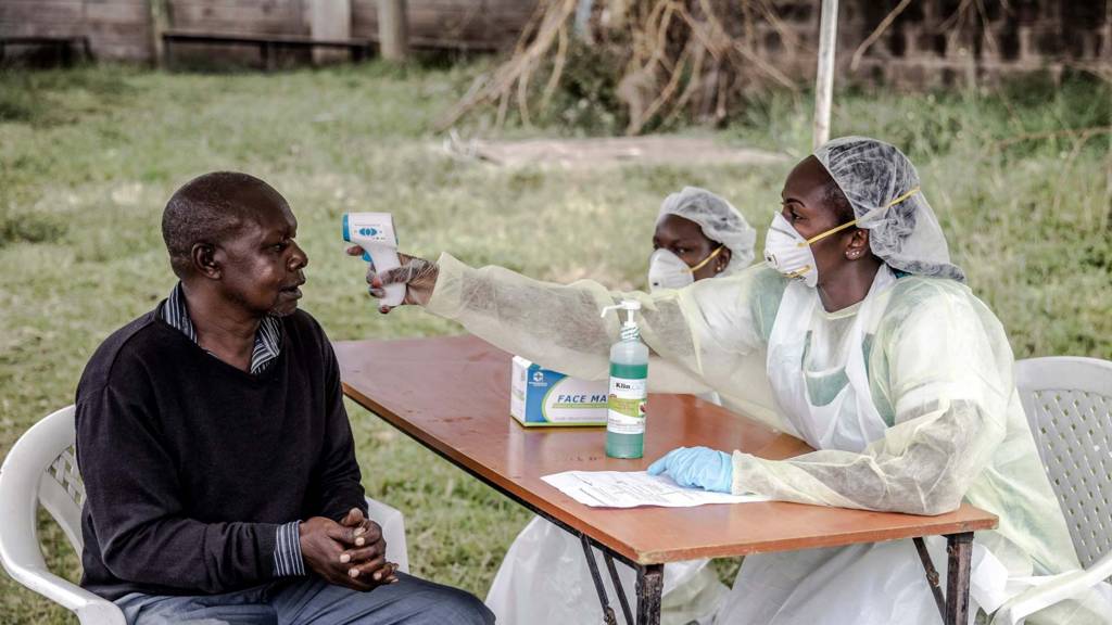 Kenyan health worker takes man's temperature with digital thermometer (18 March)