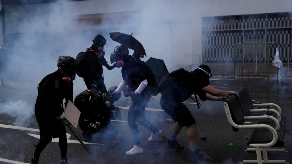 Anti-government protesters walk in tear gas during a protest in Sha Tin district, on China's National Day
