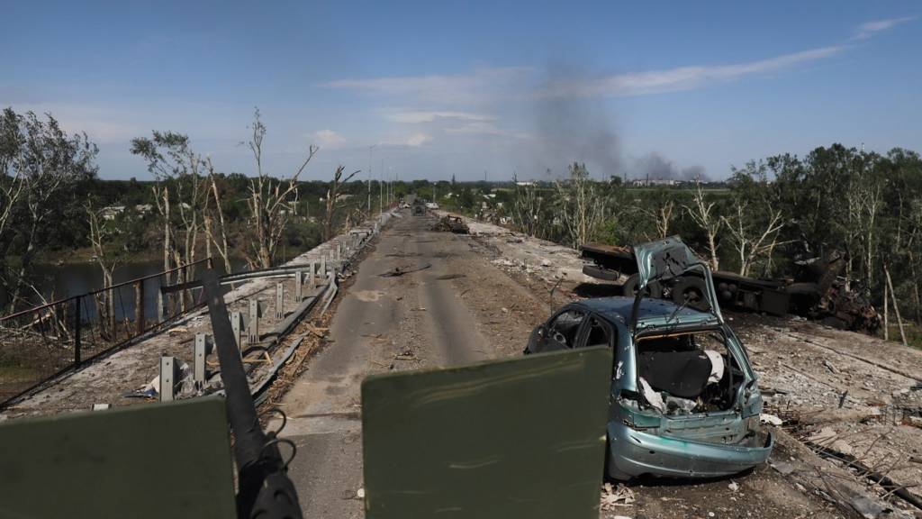 Ukrainian servicemen drive an APC on a damaged road near the front line in the city of Severodonetsk