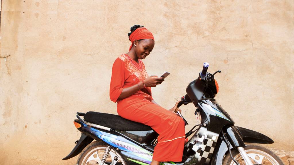 A woman in Mali on a mobile on a motorbike