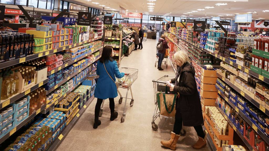 Shoppers push trolleys along an aisle inside a supermarket in the UK