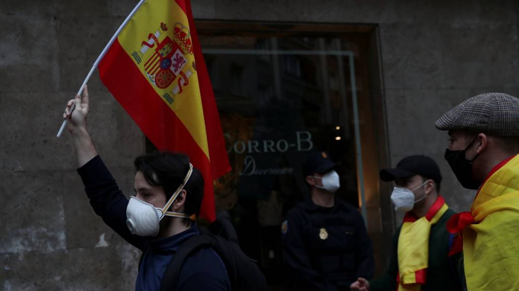 A man wearing a protective face mask carries a Spanish flag during a protest against the Spanish government's handling of the coronavirus disease in Madrid, Spain May 16, 2020