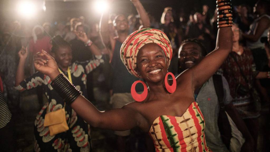 People dance and sing as they listen to Uganda's singer Jackie Akello during the 16th International African music festival 'Sauti za Busara at the Old Fort in Stone town on Tanzania's semi-autonomous archipelago Zanzibar on February 8, 2019. -