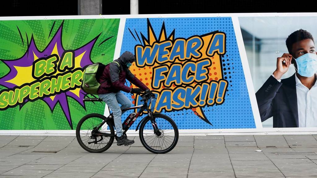 A person cycles past a sign telling people to wear a face mask in Nottingham during England"s third national lockdown to curb the spread of coronavirus