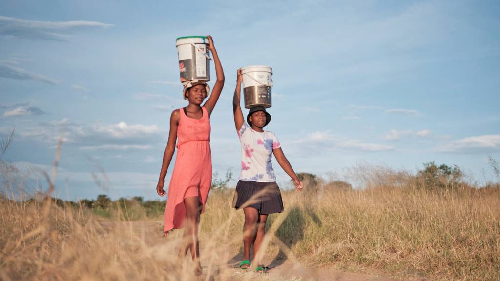 People carrying water in buckets fetched from a well in Bulawayo, Zimbabwe - March 2024