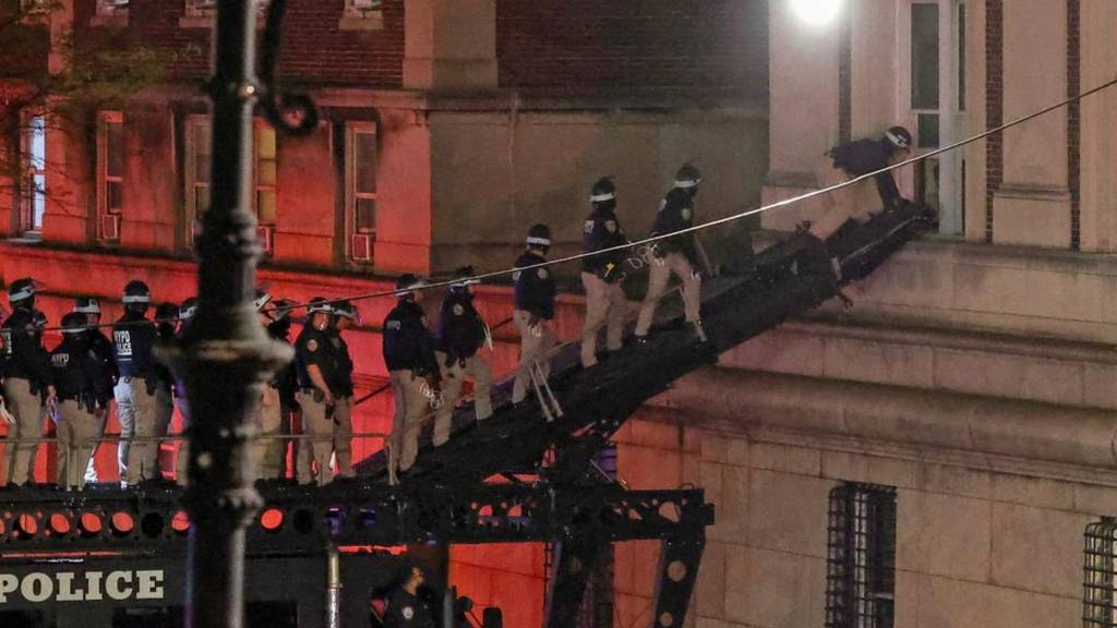 NYPD officers in riot gear break into a building at Columbia University