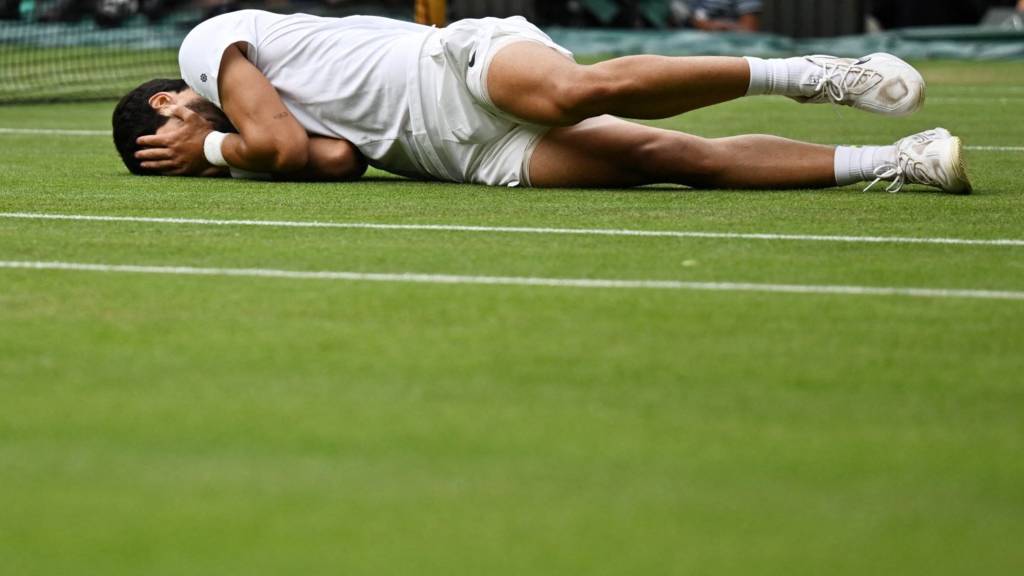 Carlos Alcaraz lies on Centre Court grass after beating Novak Djokovic in Wimbledon final