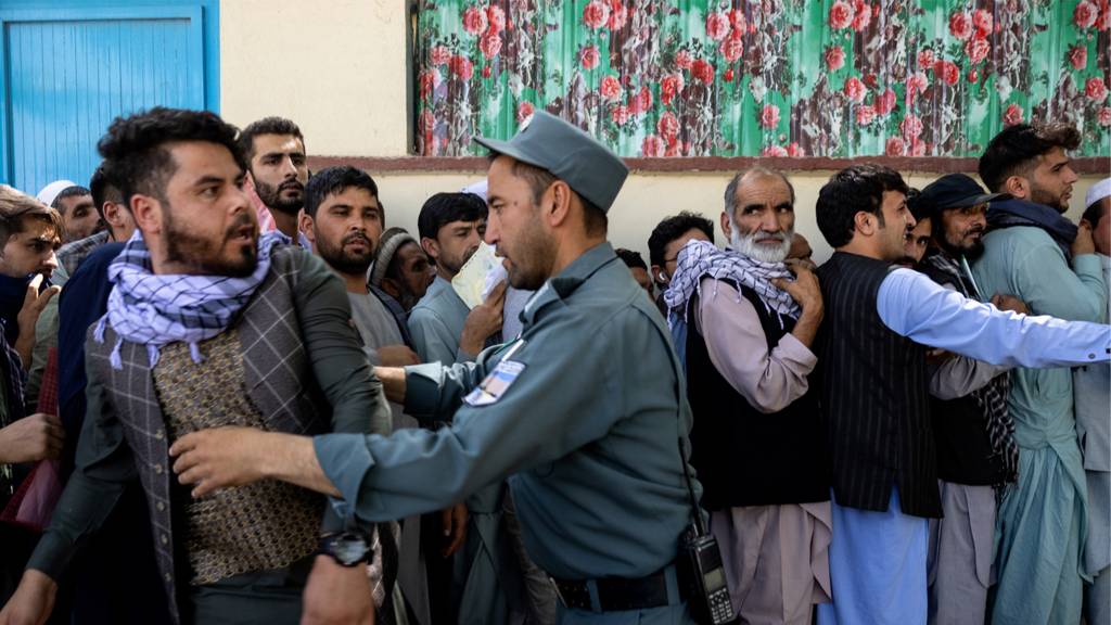 Afghans wait in long lines at the passport office on 14 August 2021 in Kabul, Afghanistan