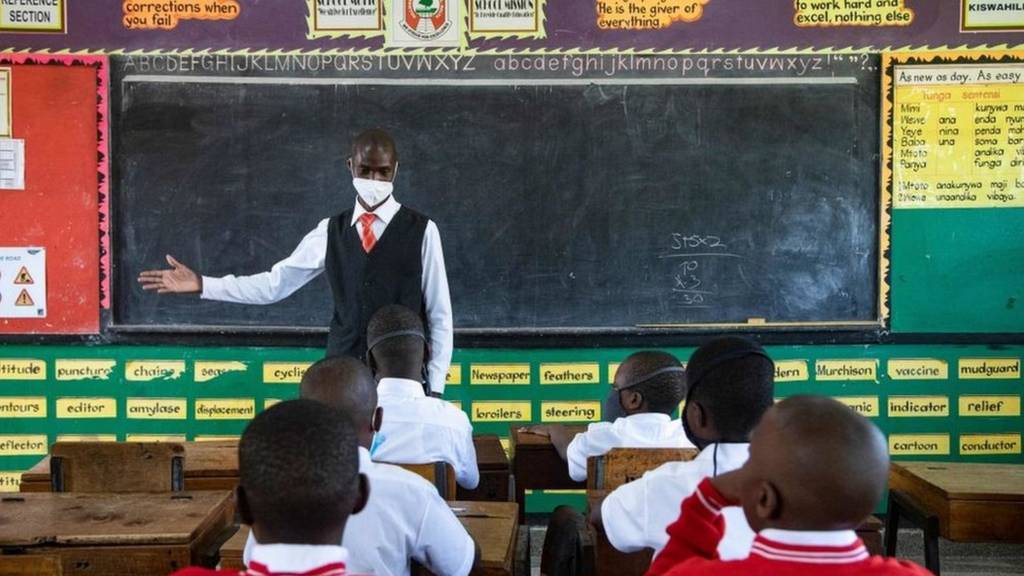 A teacher welcomes back students during a classroom lesson on day one of re-opening schools in Kampala, Uganda on January 10, 2022
