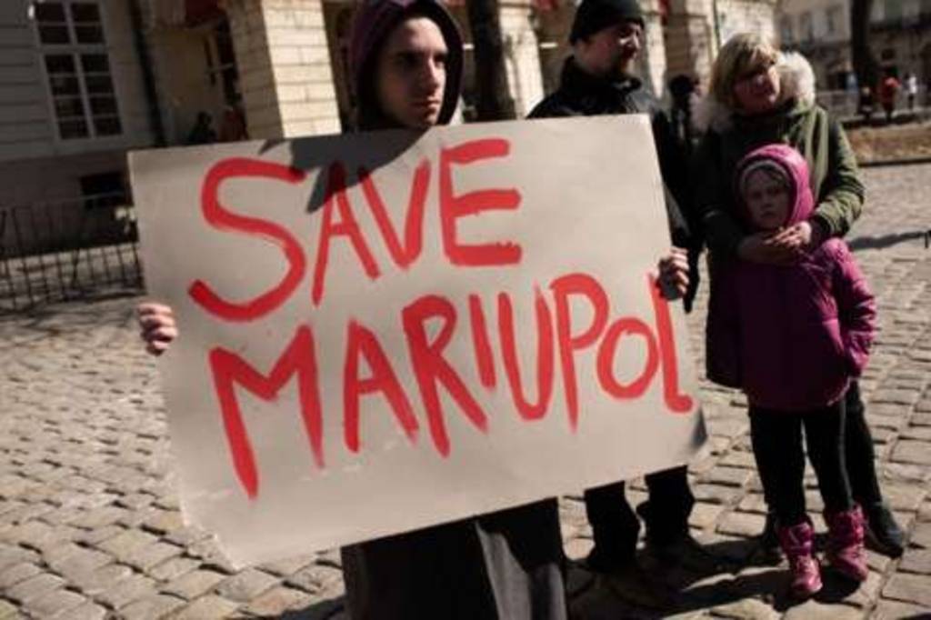 رجل يحمل لافتة كتب عليها أنقذوا ماريوبول