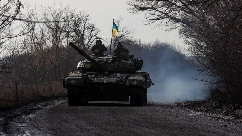 Ukrainian servicemen ride atop a tank near the frontline town of Bakhmut