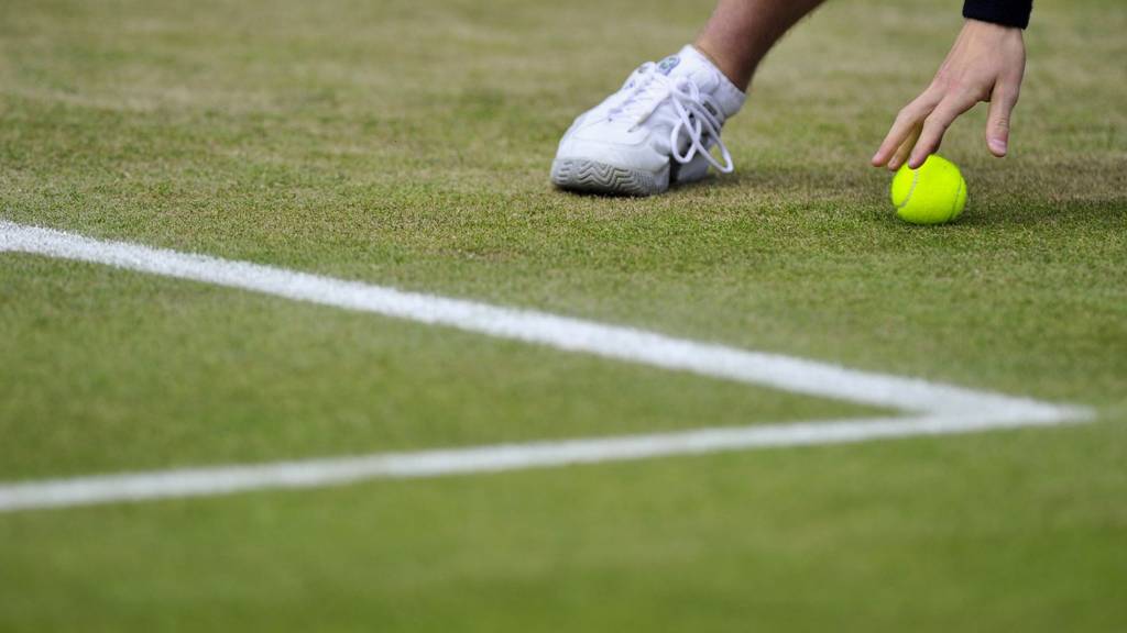 A ball boy retrieves a tennis ball during a match at Wimbledon