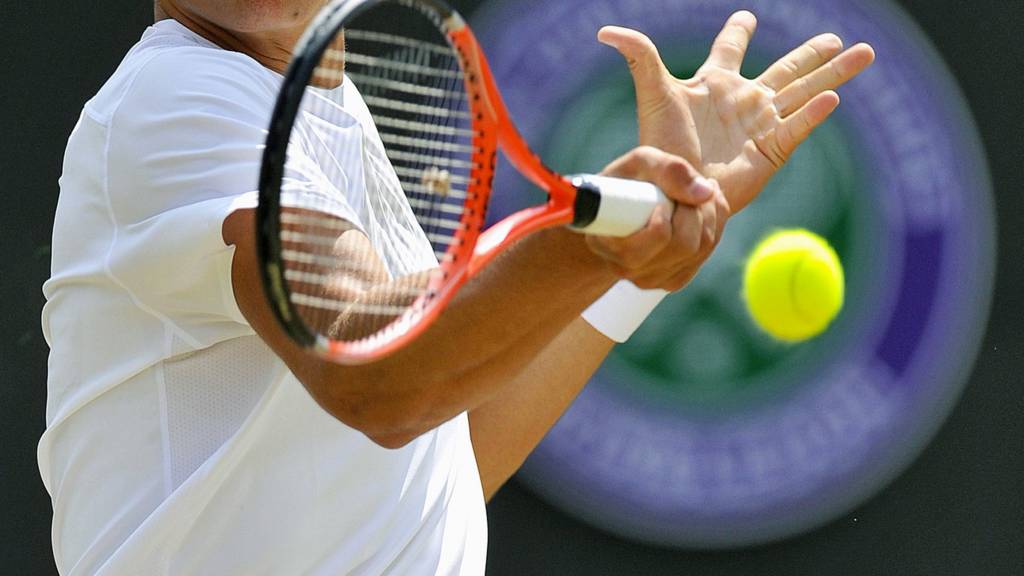 A tennis player makes a forehand shot at the Wimbledon Championships
