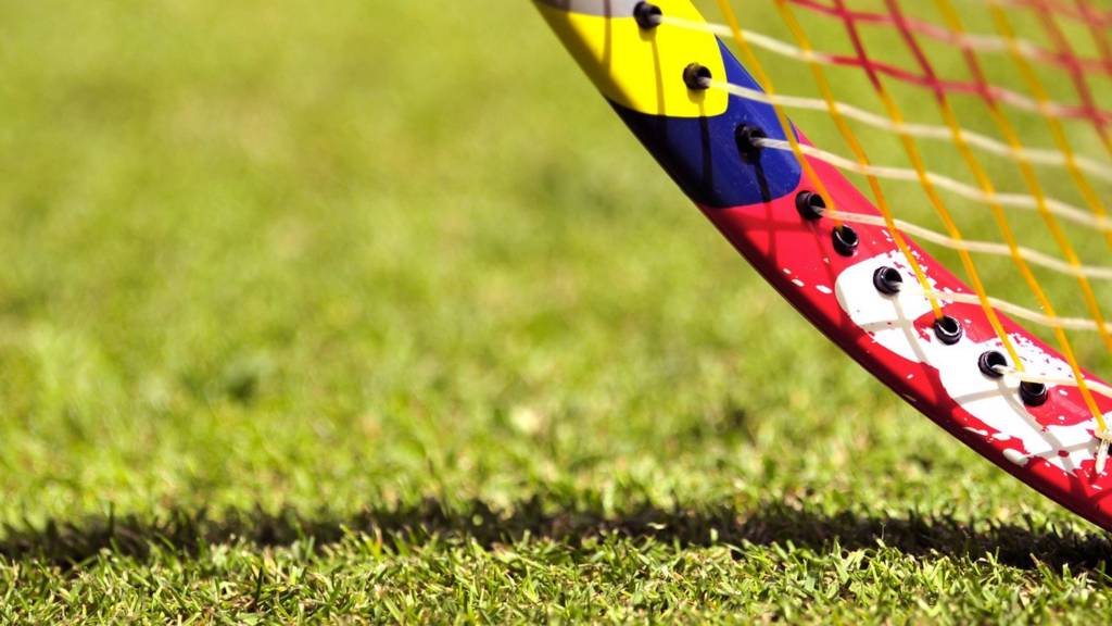 A close-up of a tennis racquet on a grass court at Wimbledon