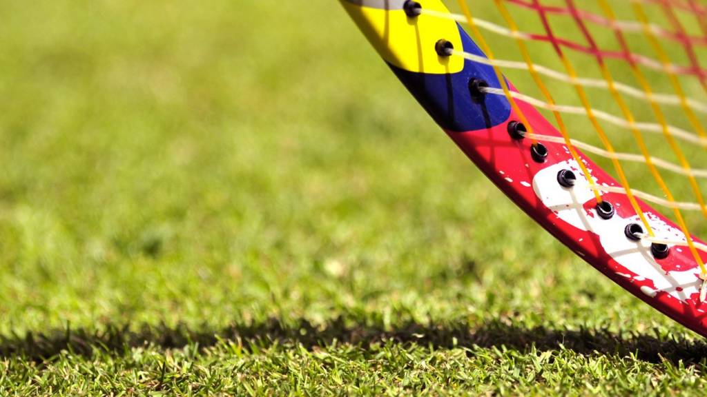 A close-up of a tennis racquet on a grass court at Wimbledon