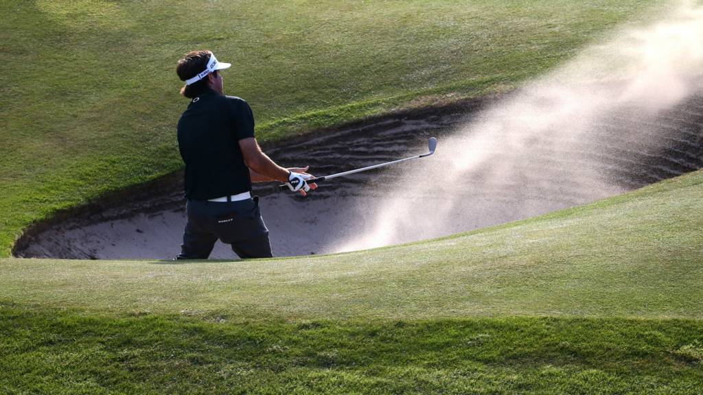A golfer takes a shot from a bunker at the 2014 Open