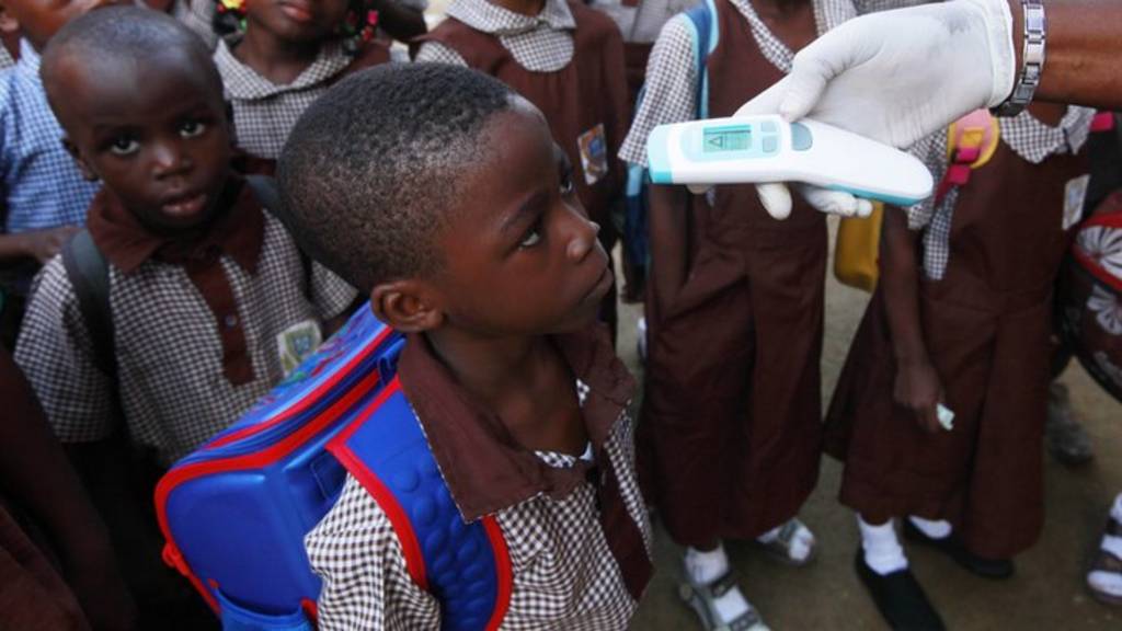 A teacher uses a thermometer to test students" temperature to check for symptoms of Ebola at Aiyetoro African Church Nursery and Primary school in Lagos, Nigeria. Wednesday, Oct. 8, 2014. Spotting any symptoms early is a key factor in treating any victims and in arresting the spread of this extremely contagious disease, according to health experts. (AP Photo/Sunday Alamba)