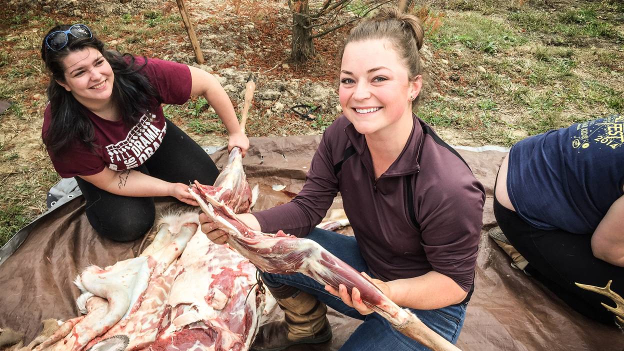 Shannon Lawn on left and Eden Kloetzli on right butchering a deer in class with stone tools they created themselves.