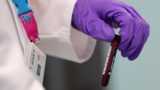 An analyst handles a vial of blood in an anti-doping laboratory
