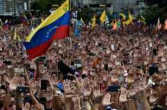 Hàng ngàn người biểu tình giơ cánh tay ủng hộ Juan Guaido khi ông tự tuyên thệ nhậm chức 'tổng thống tạm quyền' vào đúng ngày kỉ niệm cuộc đảo chính chế độ độc tài quân sự năm 1958.