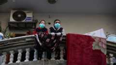 Two boys in Gaza on a balcony with protective masks on