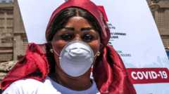 A woman wearing a mask next to a Covid-19 poster in Dakar, Senegal