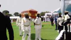 Officer in white uniforms march with the caskets.