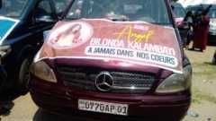 A car bonnet emblazoned with a poster in memory of one of those who died, called Bilonda Kalambayi.